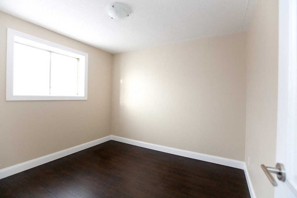 an empty room with wood floors and a window