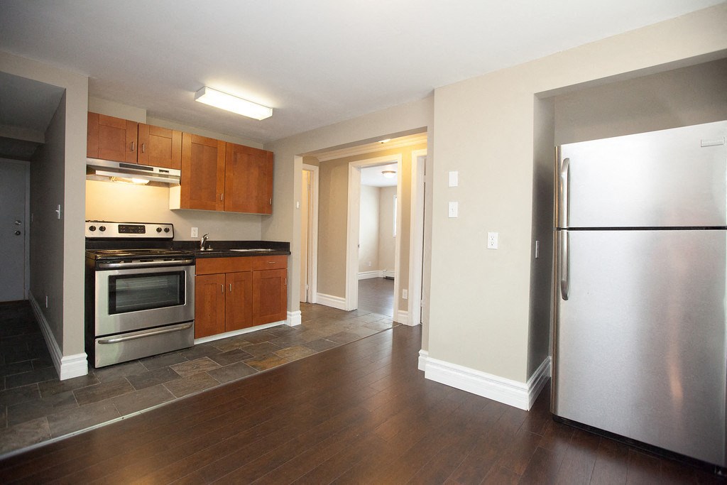 an empty kitchen with stainless steel appliances and wooden floors