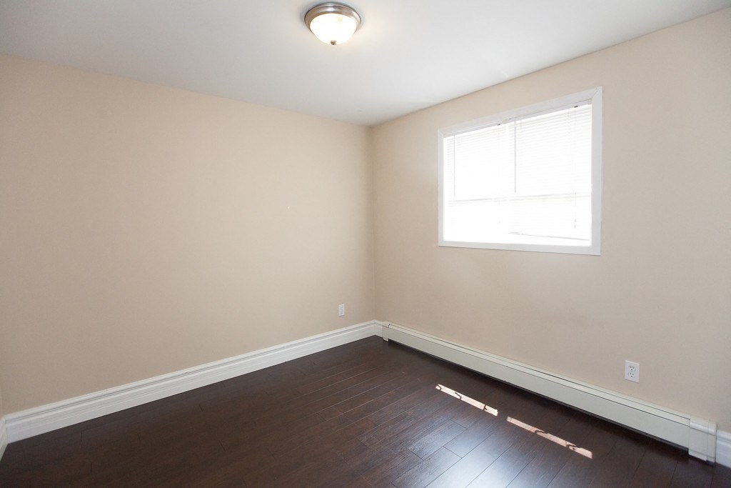 an empty room with wooden floors and a window