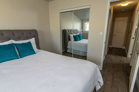 A bedroom with a large bed and a mirrored closet door.