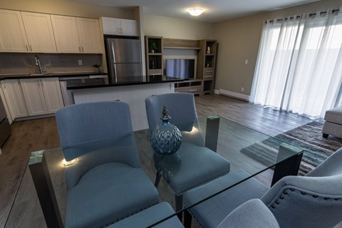 A modern living room with a glass table and grey chairs.