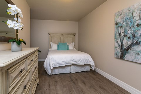 A bedroom with a bed, dresser, and painting.