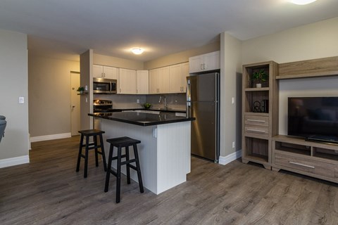 A kitchen with a black countertop and a refrigerator.