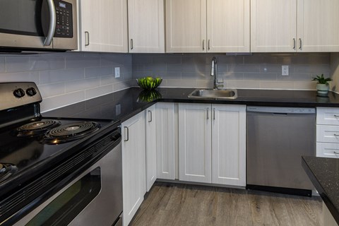 A kitchen with black countertops and white cabinets.