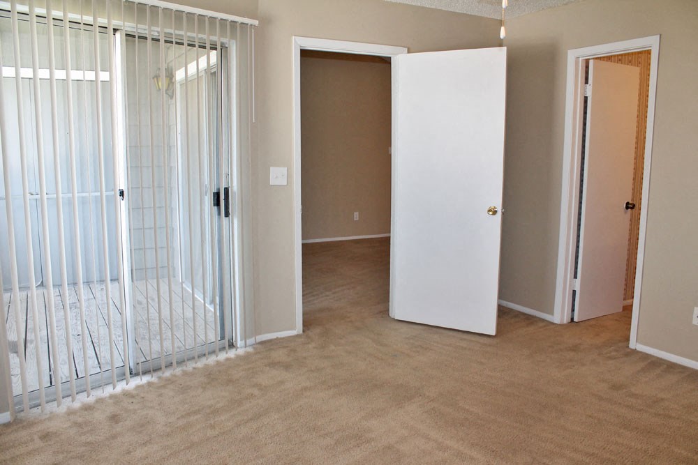 an empty living room with a mirrored closet and a door to a bedroom