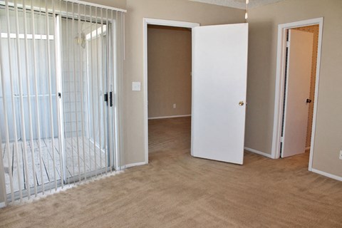 an empty living room with a mirrored closet and a door to a bedroom