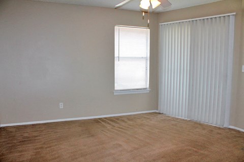 an empty living room with white blinds and a window