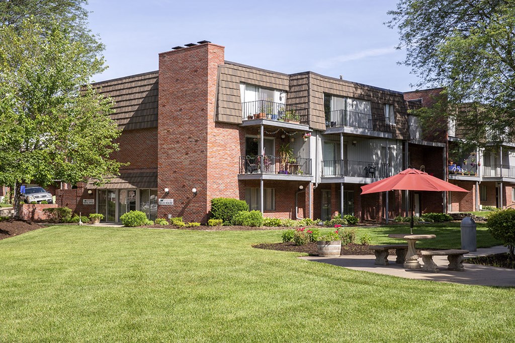 a courtyard with a picnic table and umbrella in front of a building