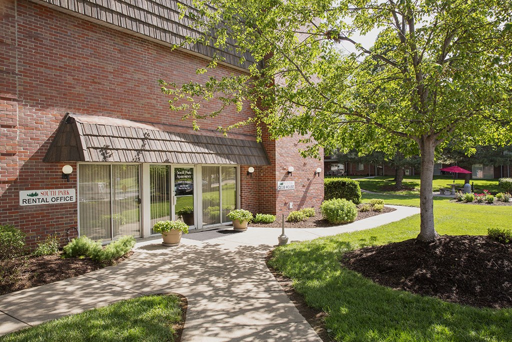 a walkway in front of a brick building with a tree