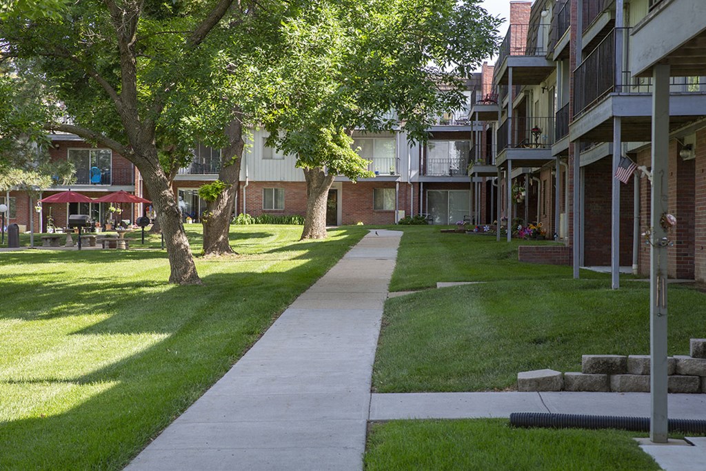 a sidewalk in the grass between two apartment buildings