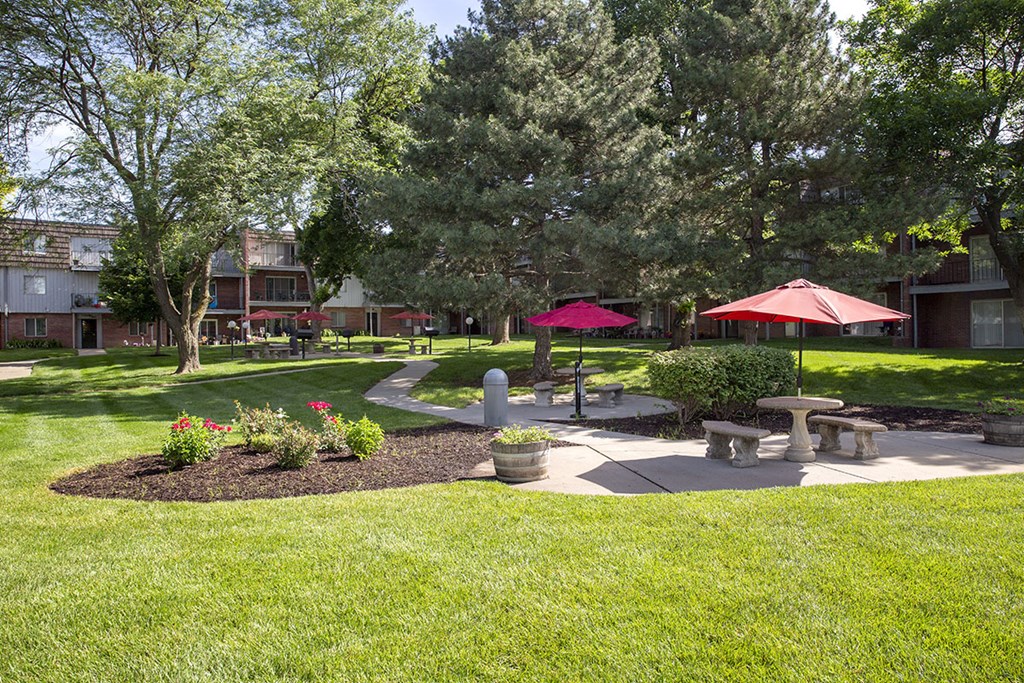 a courtyard with benches and umbrellas in a park