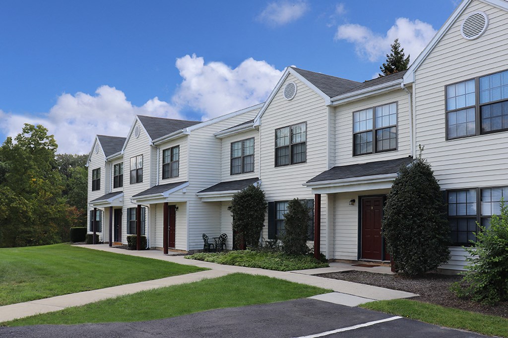 a row of white houses with a sidewalk and grass