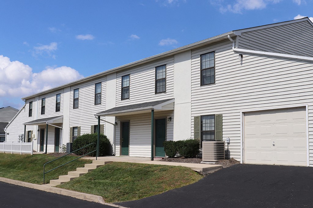 the exterior of a white house with two garage doors