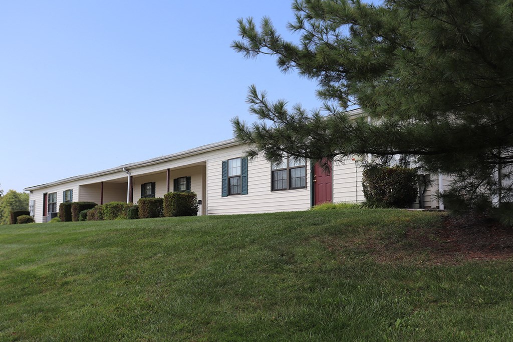 a white house with a red door sitting on a hill