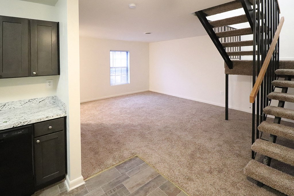 a living room with a staircase and a carpeted floor