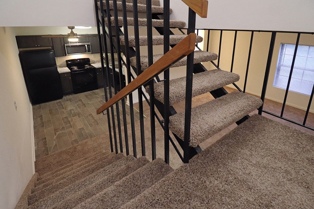a spiral staircase in a home with carpeted stairs and a kitchen