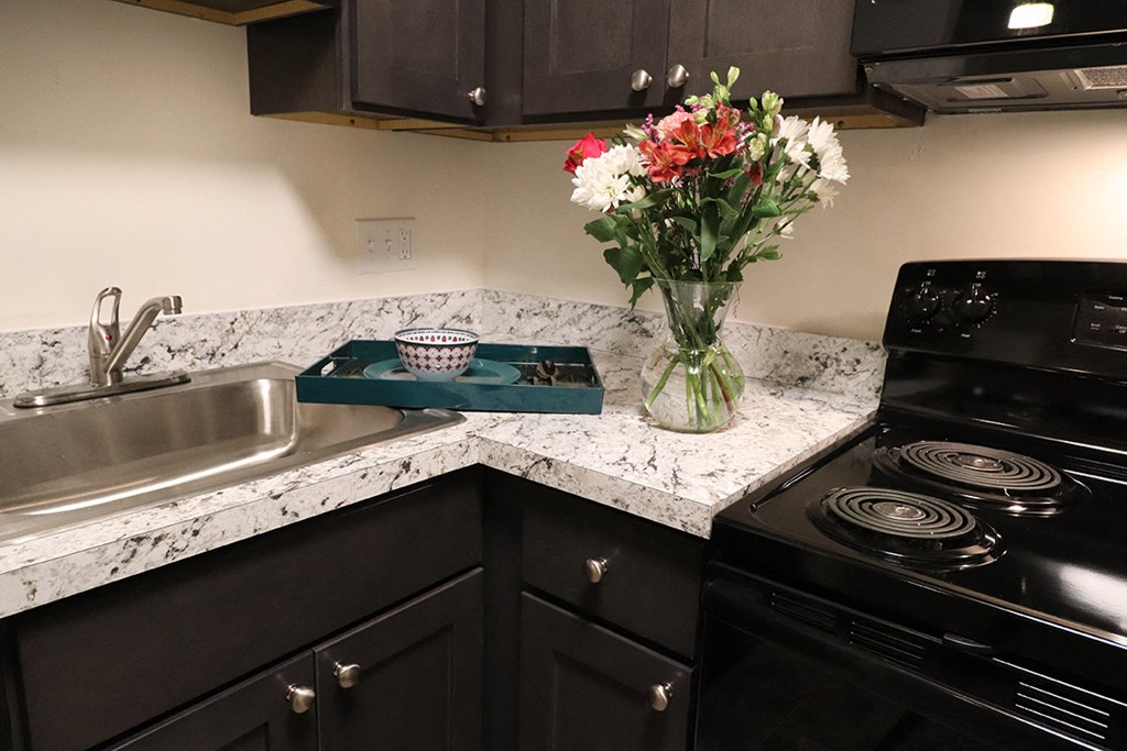 a kitchen with black appliances and a vase of flowers on a counter