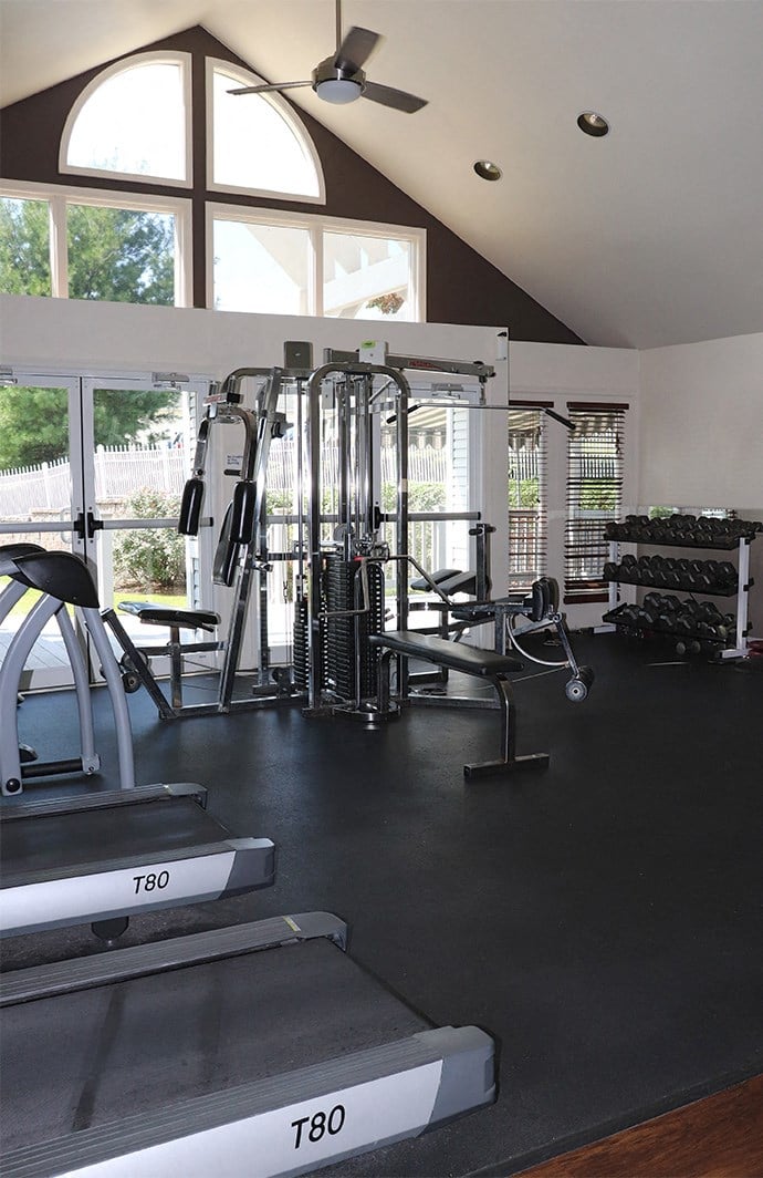 a workout room with cardio equipment and windows in a home gym