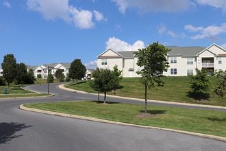 a row of houses on a grassy hill with a blue sky in the background