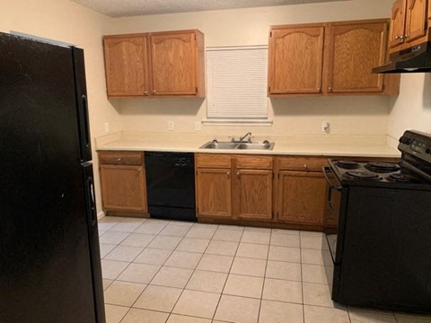 A kitchen with wooden cabinets and black appliances.