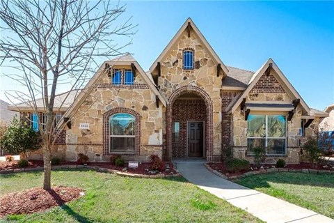 a stone house with a sidewalk in front of it