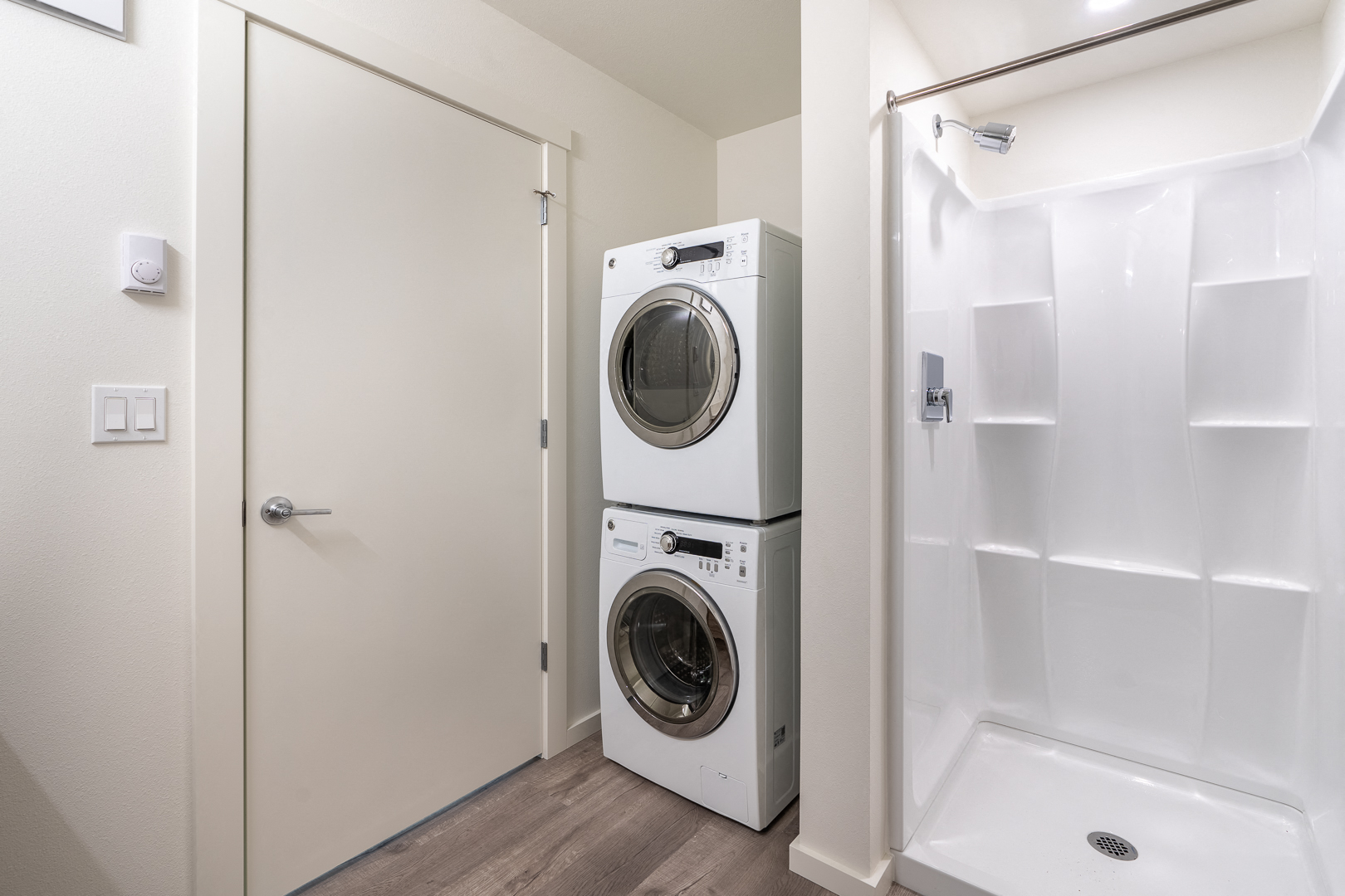 a front loading washer and dryer in a laundry room next to a shower