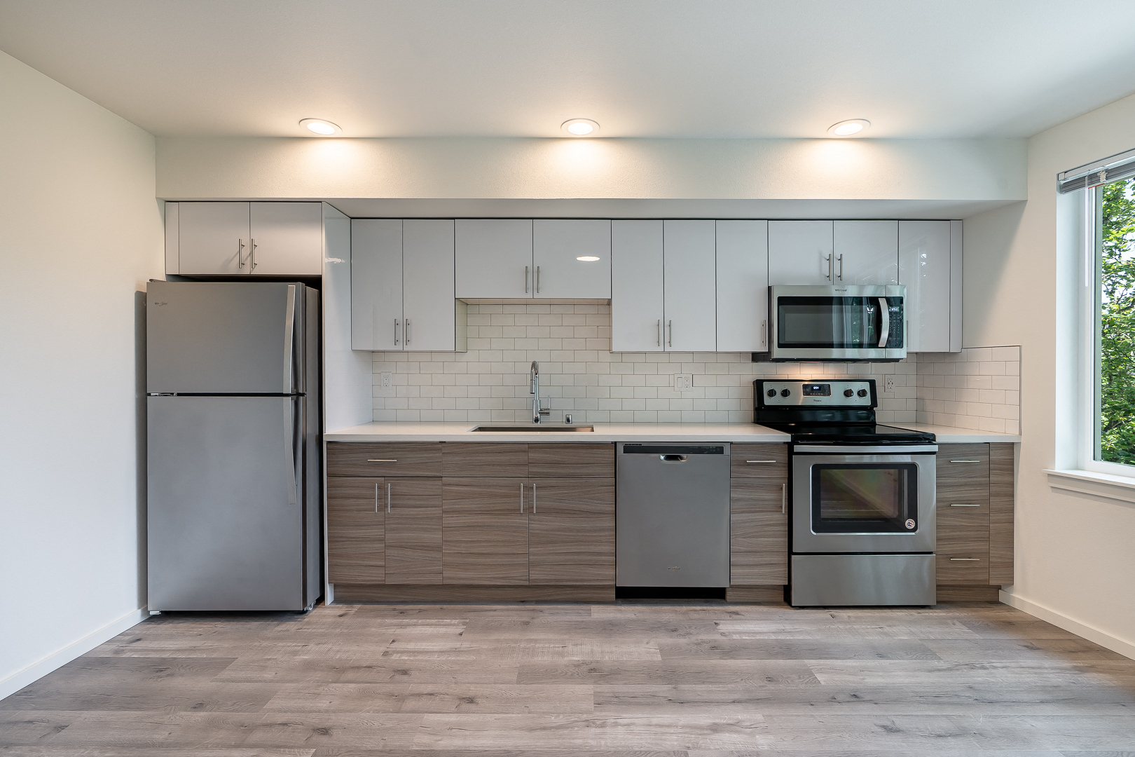 an empty kitchen with stainless steel appliances and white cabinets