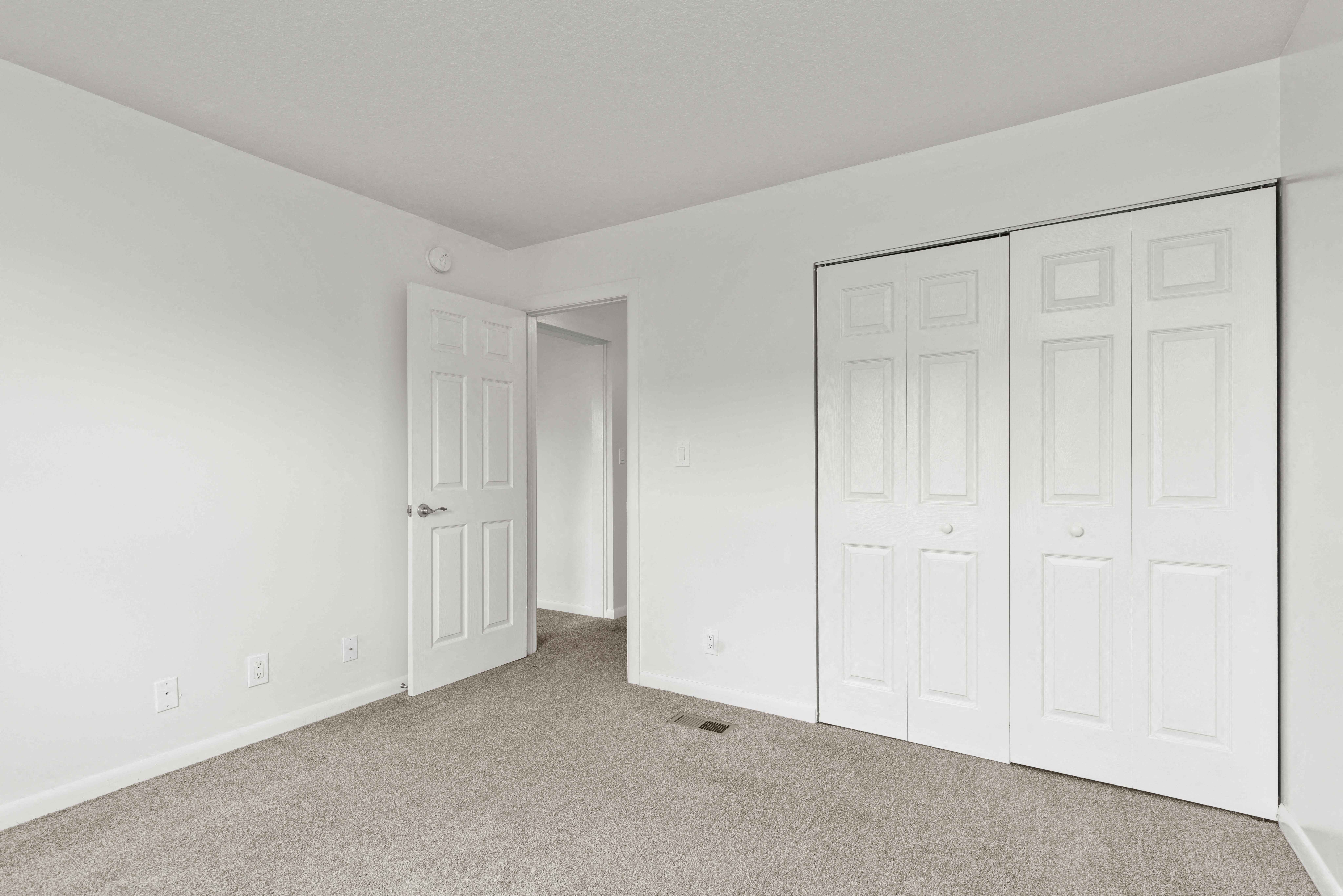 A white room with a carpeted floor and a white door.