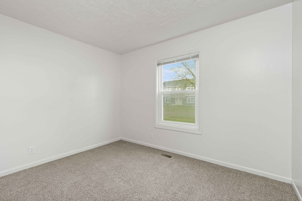 A room with a window and carpeted floor.