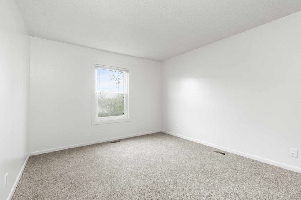A room with a carpeted floor and a window.