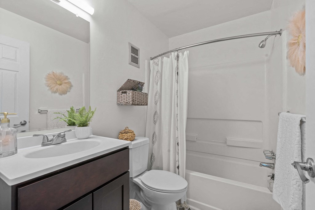 A white bathroom with a toilet, sink, and shower.