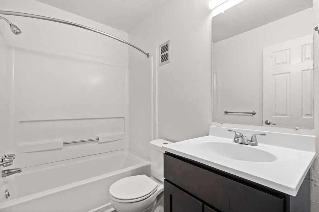 A white bathroom with a toilet, sink, and bathtub.