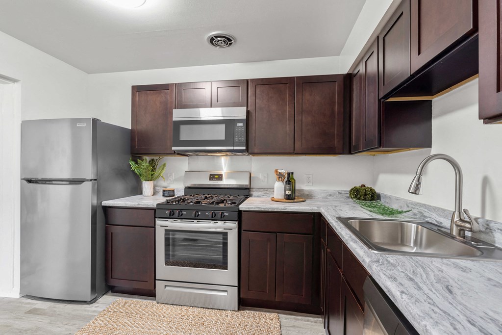 A kitchen with brown cabinets and a stainless steel refrigerator.