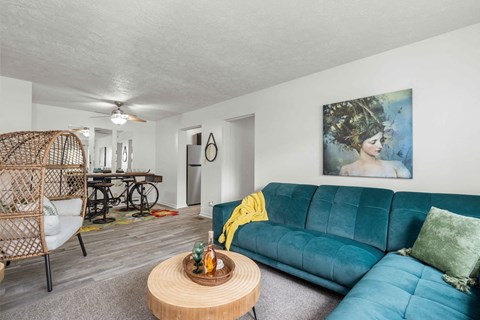 A living room with a blue couch and a painting of a woman on the wall.