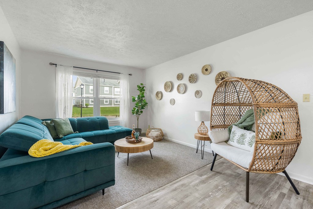 A living room with a green couch and a wicker chair.