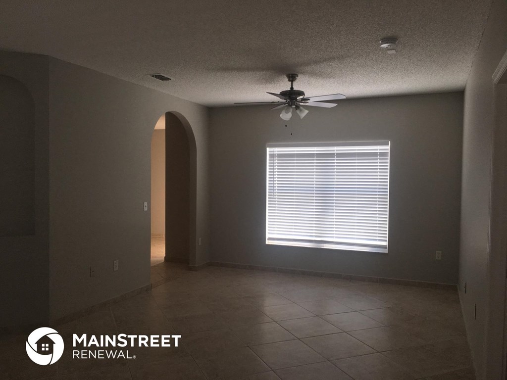 an empty living room with a ceiling fan and a window
