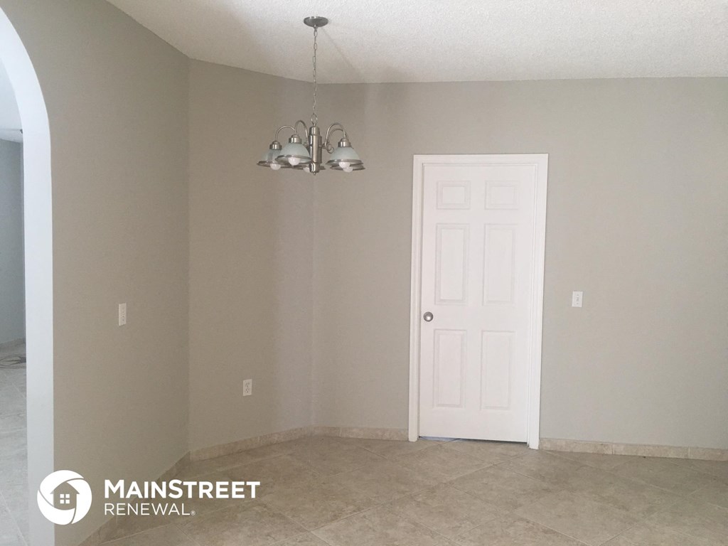 the living room of a house with a white door and a chandelier