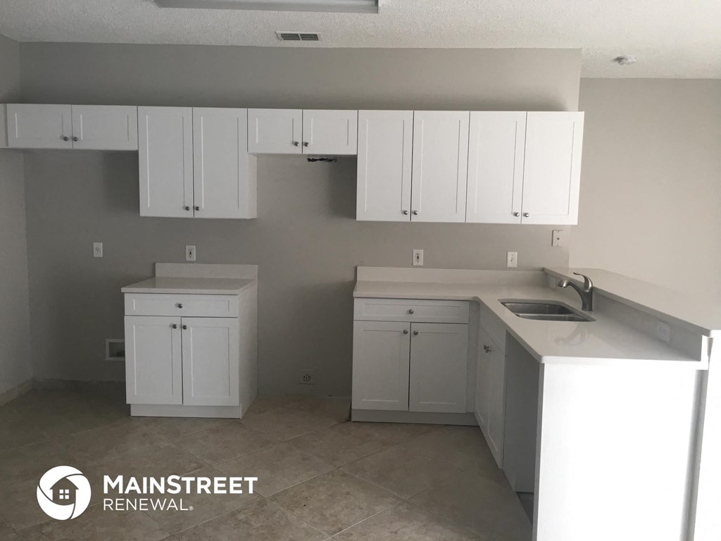 an empty kitchen with white cabinets and a sink