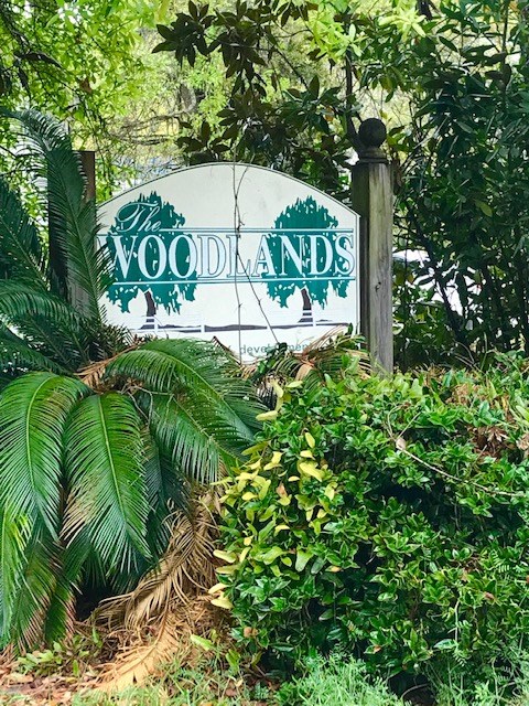 a sign for woodlands in the middle of trees and plants