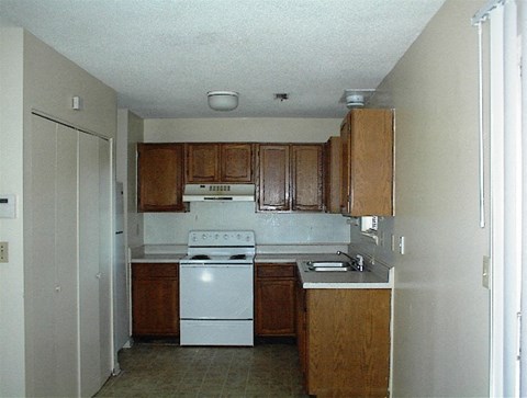 A kitchen with a white stove and wooden cabinets.