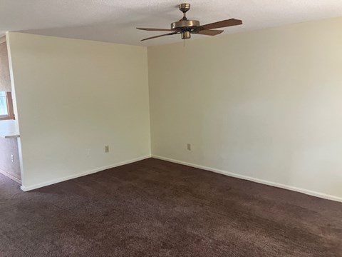 A room with a ceiling fan and carpeted floor.