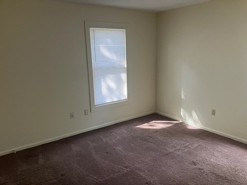 A room with a window and carpeted floor.