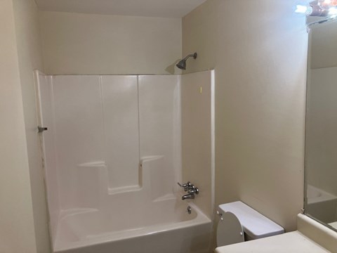 A white bathroom with a tub, toilet and sink.