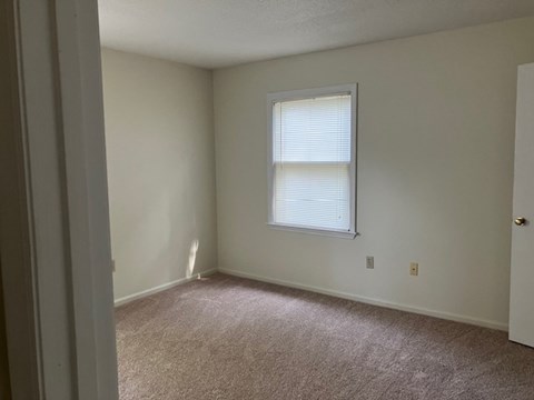 A room with a window and carpeted floor.