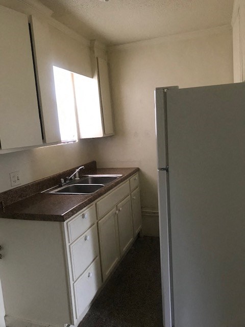A kitchen with white cabinets and a brown counter top.