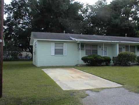 A house with a green front yard and a concrete walkway leading to the front door.