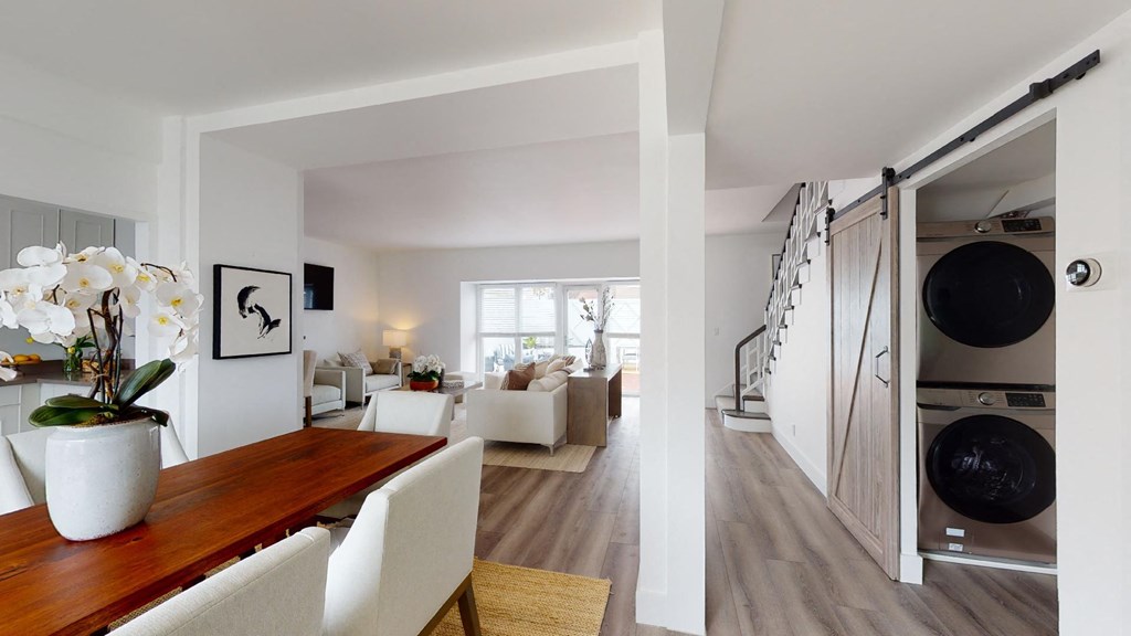 a living room and dining room with white furniture and a staircase