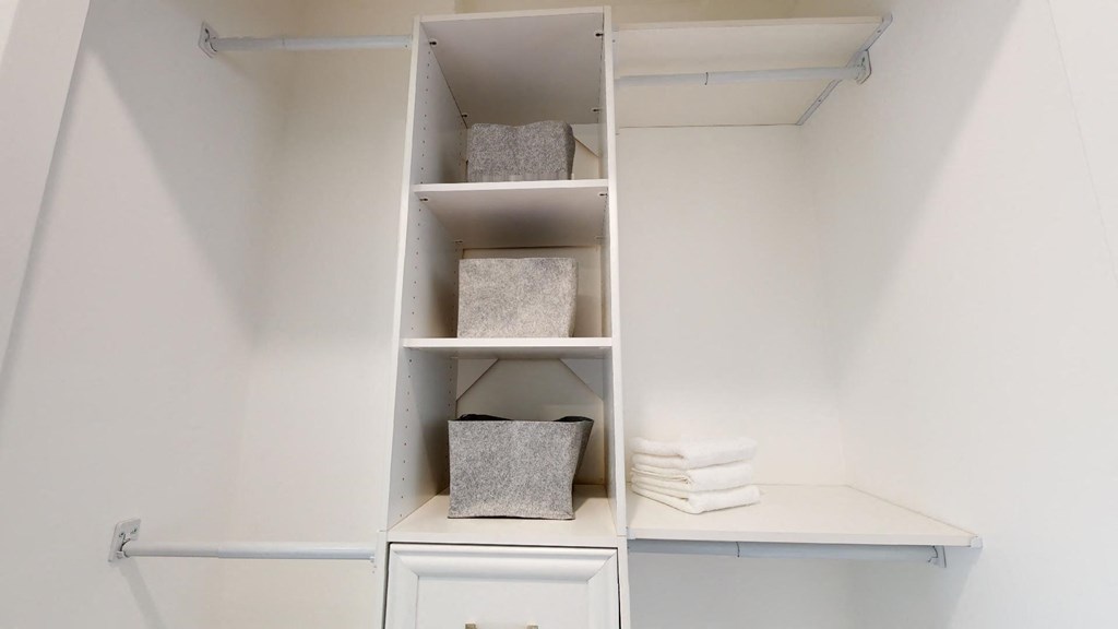a closet with shelves and drawers and folded towels