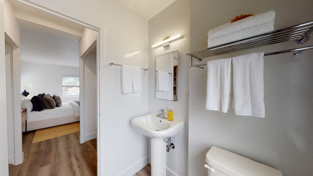 a bathroom with a sink and a mirror    and a bedroom