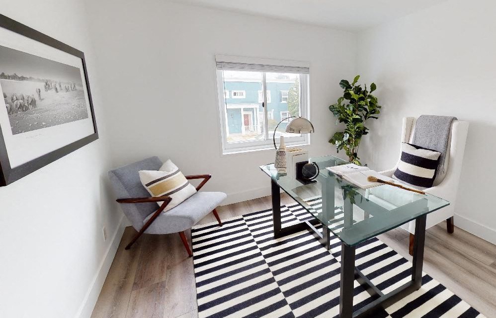a living room with a glass desk and a striped rug